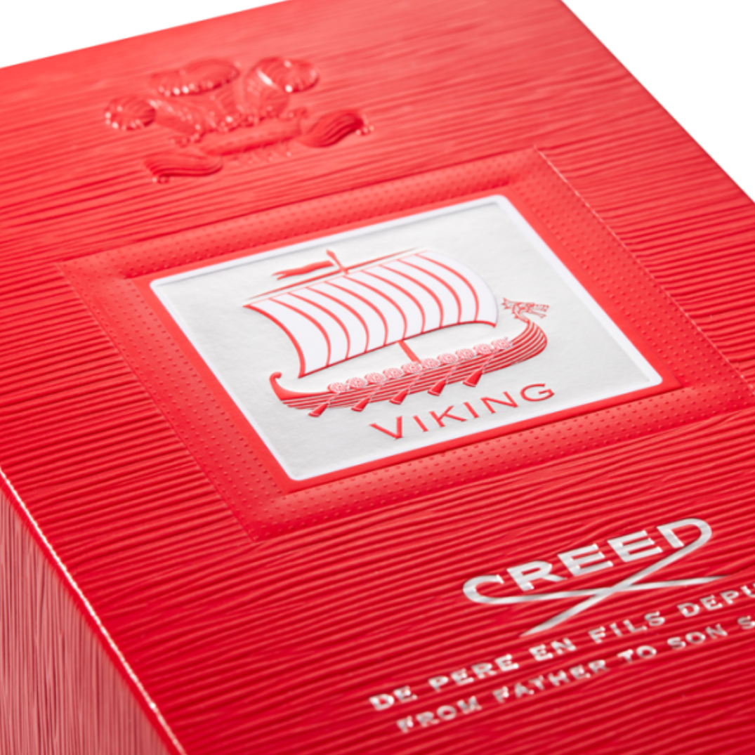 Close-up of Creed Viking Eau de Parfum 100 ml box texture with embossed logo and vivid red finish, symbolizing the fragrance’s strength, luxury, and masculine energy.