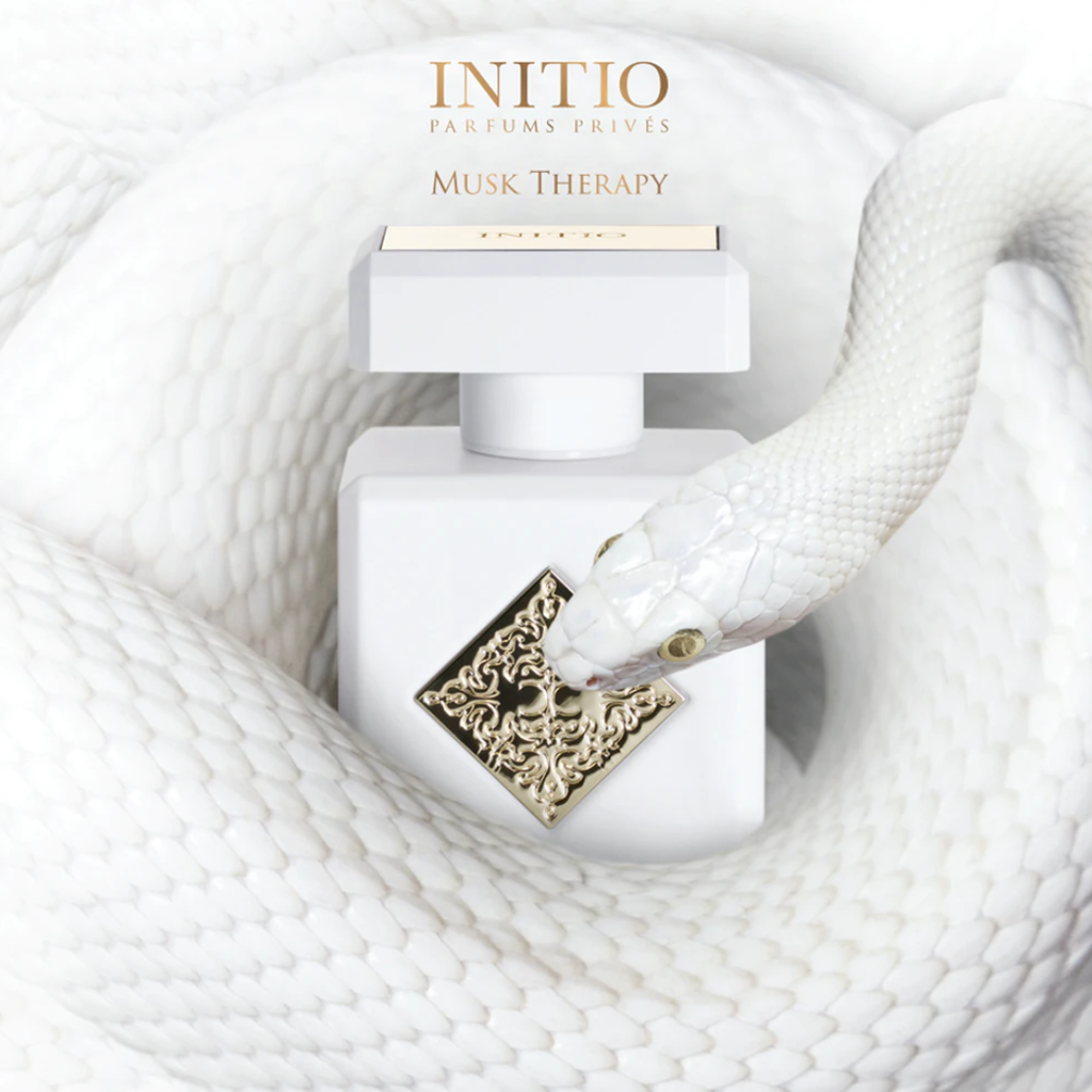 Initio Musk Therapy Extrait 90 ml bottle displayed on soft white fabric in a refined lifestyle setting. A serene and uplifting unisex perfume featuring magnolia, bergamot, and white musk.
