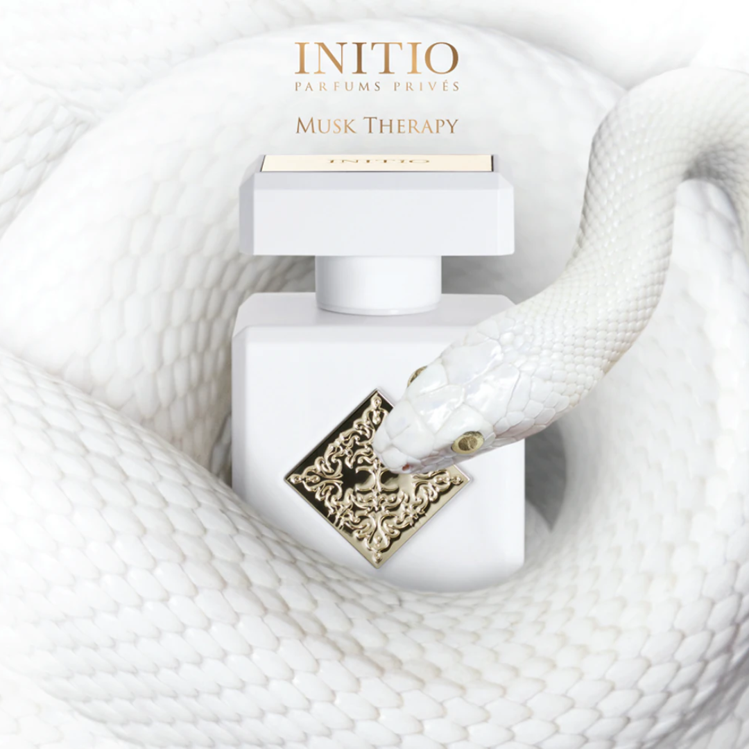 Initio Musk Therapy Extrait 90 ml bottle displayed on soft white fabric in a refined lifestyle setting. A serene and uplifting unisex perfume featuring magnolia, bergamot, and white musk.
