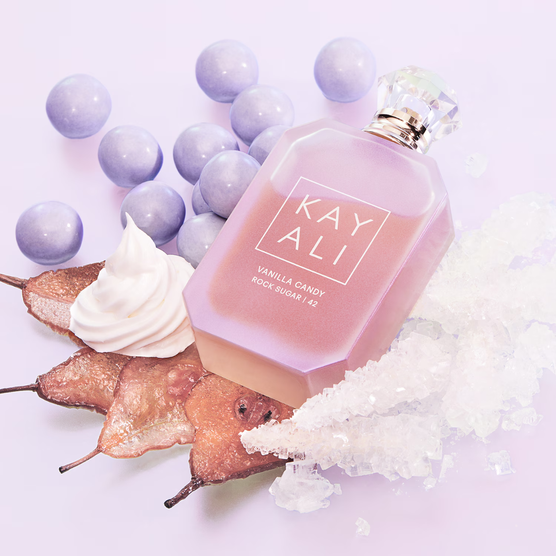 Kayali Vanilla Candy Rock Sugar 42 EDP 100 ml perfume bottle showcased beside bubble gum, pear, and vanilla accents. A sweet and addictive gourmand scent with caramel, patchouli, and tonka bean — perfect for spring and summer. Shop Fragrance Emporium.