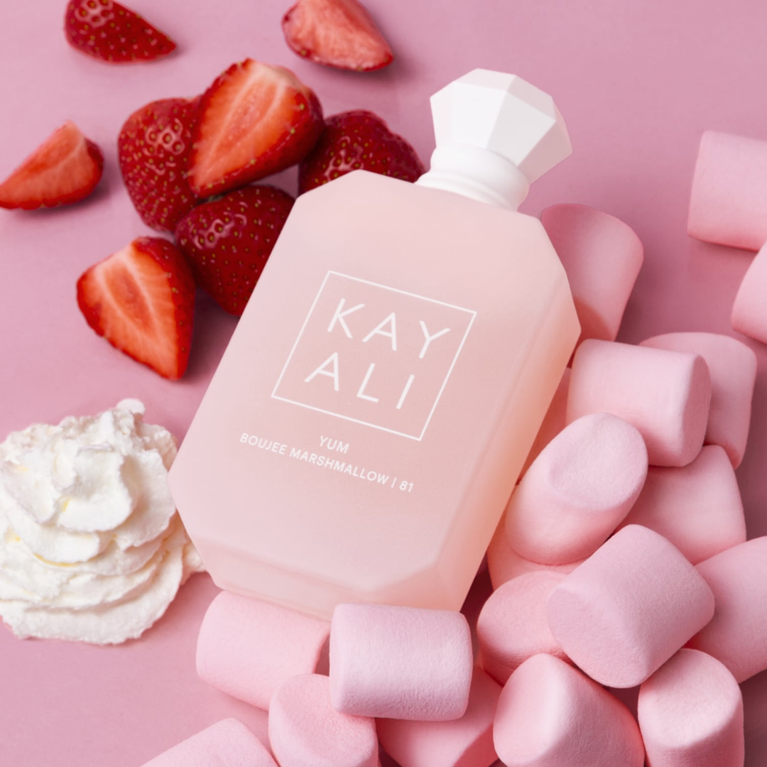 Kayali Yum Boujee Marshmallow 81 EDP 100 ml perfume bottle styled beside marshmallows, strawberries, and vanilla elements. A delectable blend of whipped cream, freesia, coconut, and sugar, radiating feminine luxury and irresistible sweetness. Shop at Fragrance Emporium.