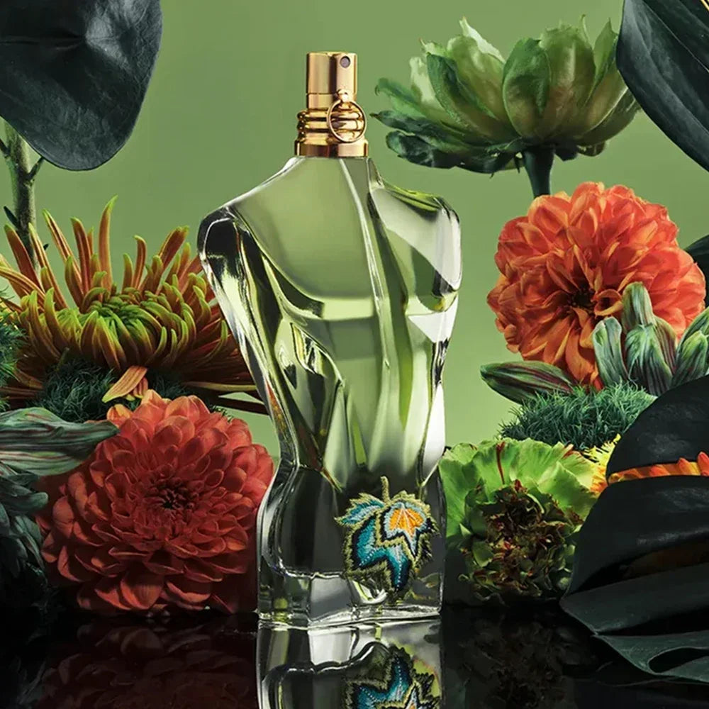 Jean Paul Gaultier Le Beau Paradise Garden Eau de Parfum bottle surrounded by exotic red and green tropical flowers, symbolizing its paradise-inspired scent.